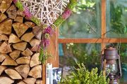 Moderner Landhausstil: Feuerholz als Wanddekoration, farbig lasierte Möbel und dazu passend ein Heideherz aus Erica darleyensis und pinken Callunen.