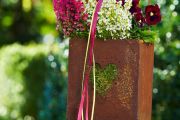 Ideal als Begrenzung für Gartenwege: Kleine rostige Blumenkästen, die an einer ebenso rostigen Metallstange aufgehängt werden können. © Azerca